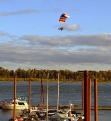 Person Flying over Water on Powered Parachute